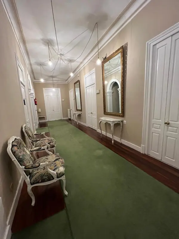 Un long couloir d'hôtel avec des portes blanches de chaque côté et un tapis vert.