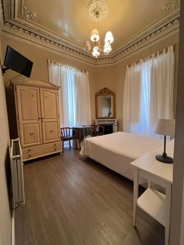 Une chambre lumineuse avec un lit, une commode et un miroir.