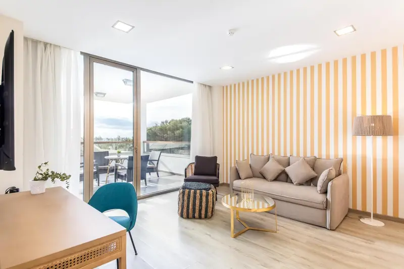 Espace de séjour lumineux avec canapé et accès à une terrasse.