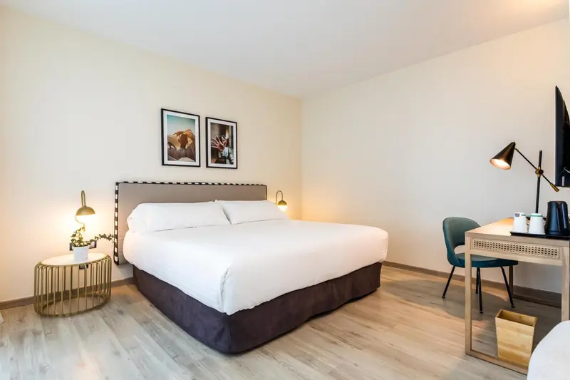 Une chambre lumineuse avec un grand lit et un bureau.