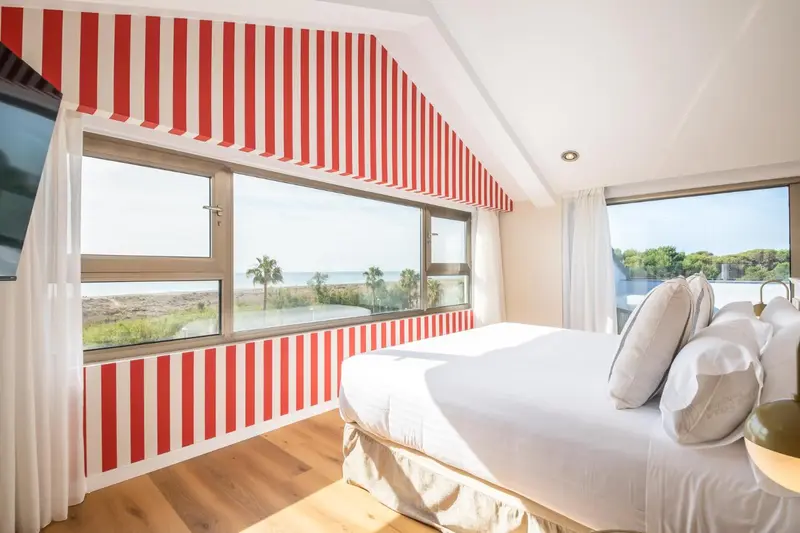 Une chambre lumineuse avec un lit fait et une vue sur la mer.
