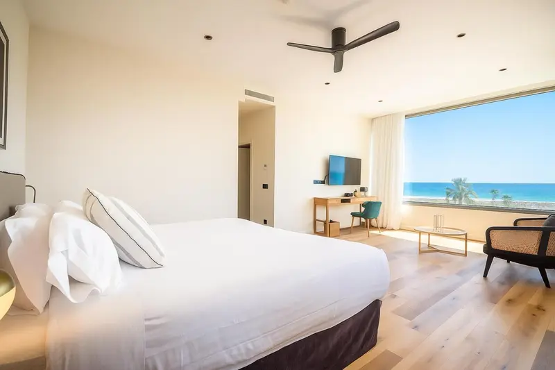 Une chambre lumineuse avec un grand lit et une vue sur la mer.