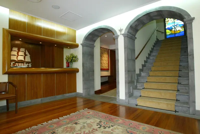 Un comptoir d'accueil en bois se trouve dans un hall d'entrée avec un escalier.