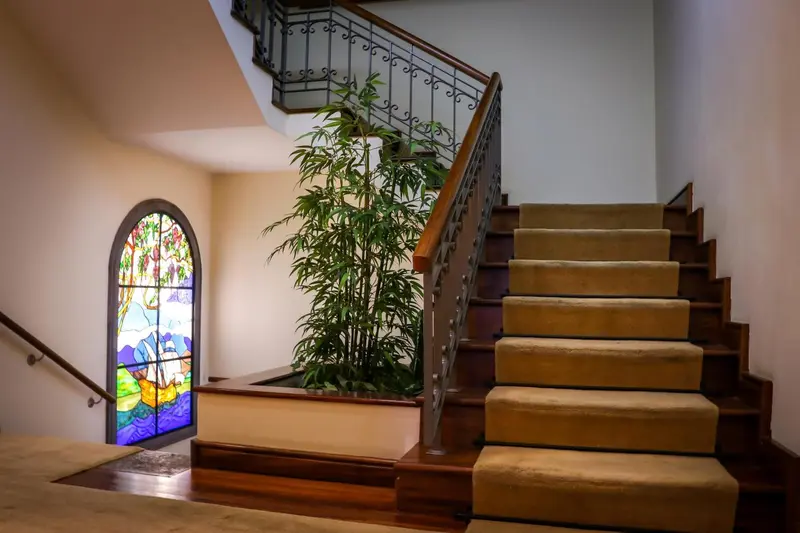 Un escalier en bois mène à l'étage supérieur, éclairé par une fenêtre vitrail.