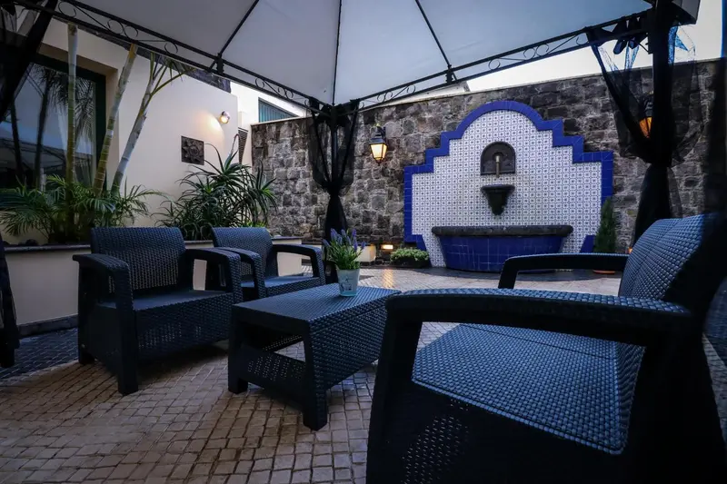 Espace extérieur aménagé avec des fauteuils et une fontaine décorative.