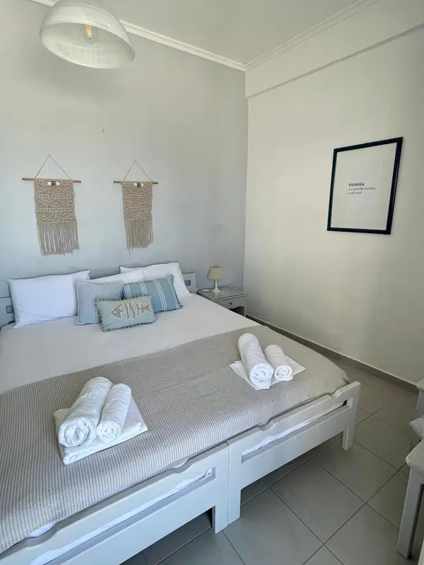 Une chambre lumineuse avec un grand lit décoré de coussins et de serviettes roulées.