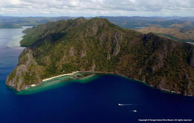 Vue aérienne d'une île tropicale verdoyante entourée d'eaux turquoise.