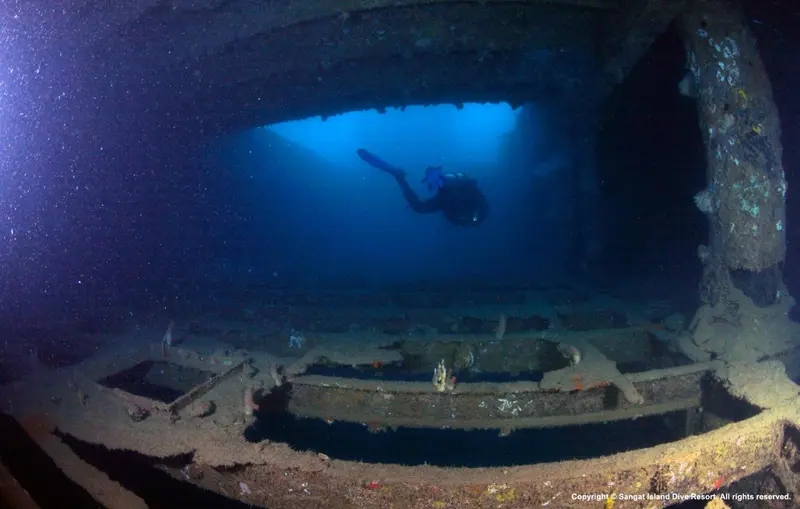Un plongeur explore l'intérieur d'une épave sous-marine.