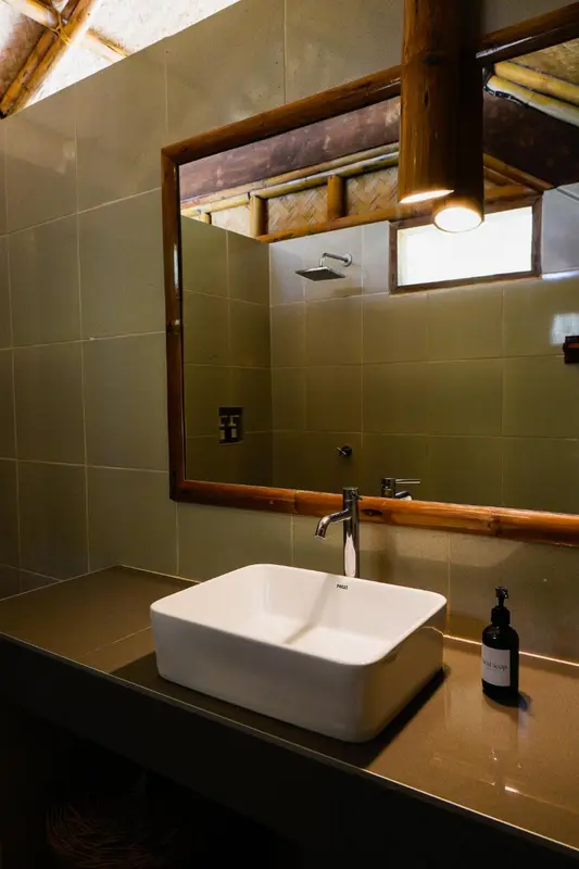 Un lavabo blanc est installé devant un miroir dans une salle de bain carrelée.