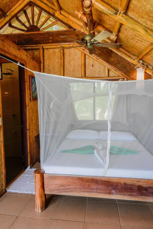 Une chambre avec un lit recouvert d'une moustiquaire et un décor en bois.