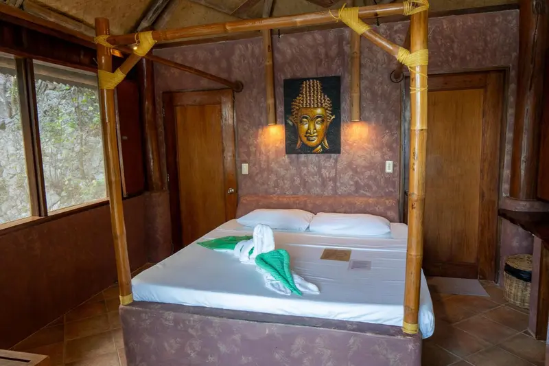Une chambre avec un grand lit recouvert d'une moustiquaire en bambou et une décoration murale.