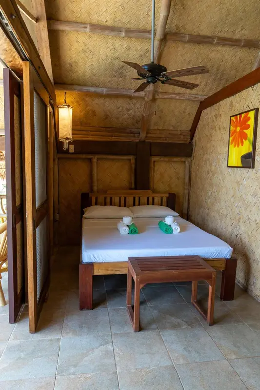 Une chambre lumineuse avec un lit fait et une décoration tropicale.