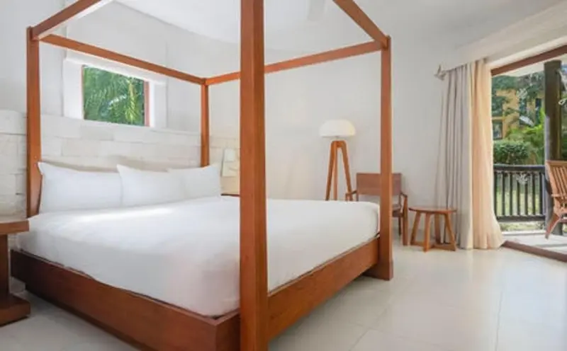 Une chambre lumineuse avec un grand lit à baldaquin et une décoration sobre.