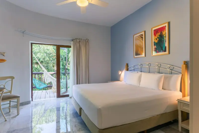 Une chambre lumineuse avec un grand lit et un accès à une terrasse.