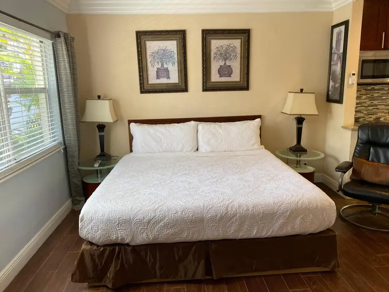 Une chambre lumineuse avec un grand lit recouvert d'une courtepointe blanche.
