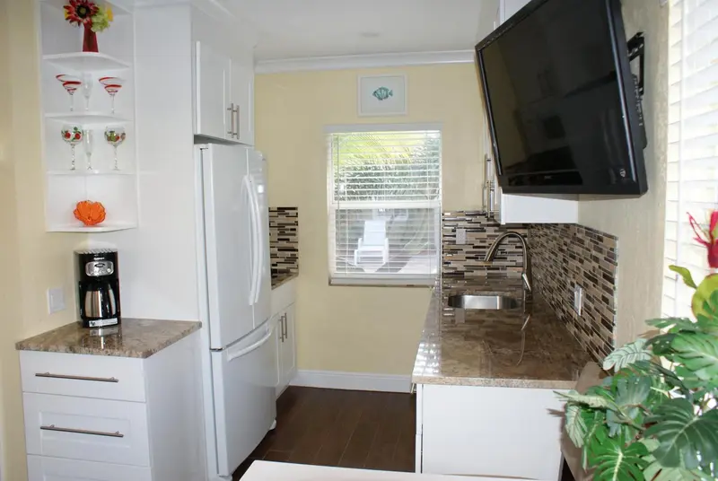 Une kitchenette lumineuse avec un réfrigérateur blanc et un plan de travail.