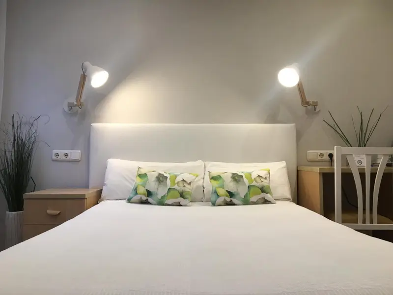 Un lit double avec des oreillers blancs et verts dans une chambre lumineuse.
