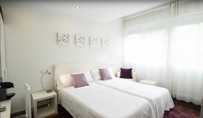 Une chambre lumineuse avec un lit double et des oreillers violets.