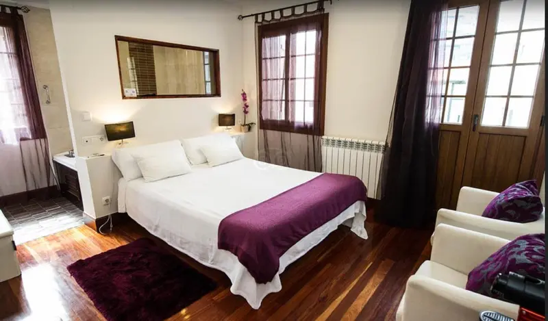 Une chambre lumineuse avec un grand lit recouvert d'une couverture violette et des meubles en bois.