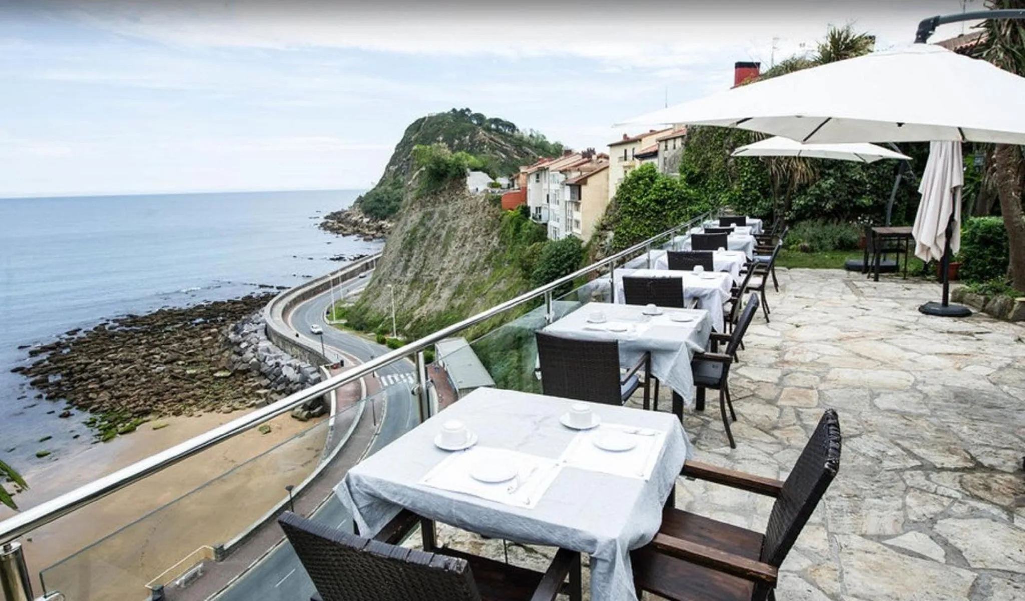 Terrasse de restaurant avec vue sur la côte rocheuse et la mer.