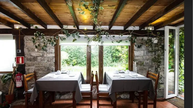 Une salle à manger lumineuse avec des tables dressées devant de grandes fenêtres.