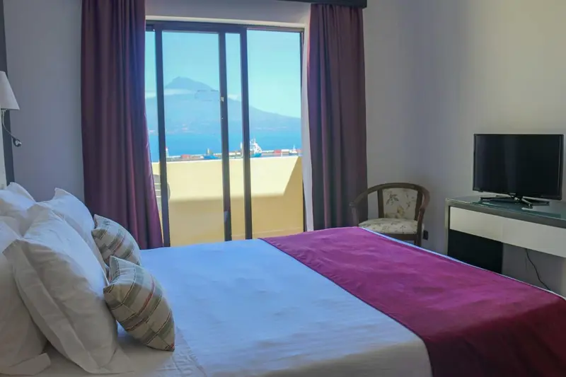 Chambre avec un grand lit donnant sur une vue dégagée.
