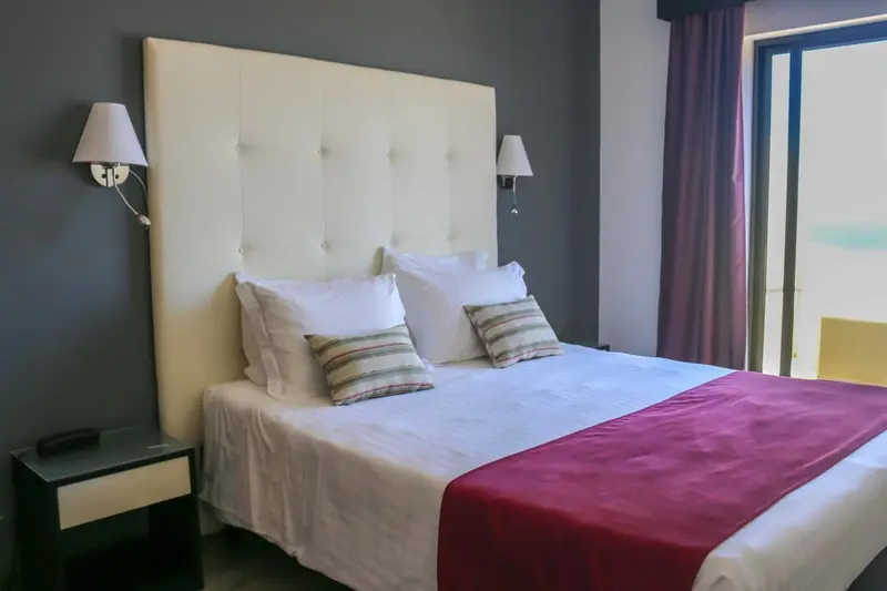 Un lit double avec une tête de lit blanche et des oreillers décorés dans une chambre.