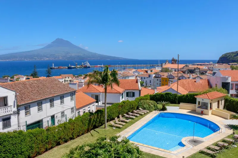 Vue aérienne d'un complexe hôtelier avec piscine et vue sur la mer et un volcan.