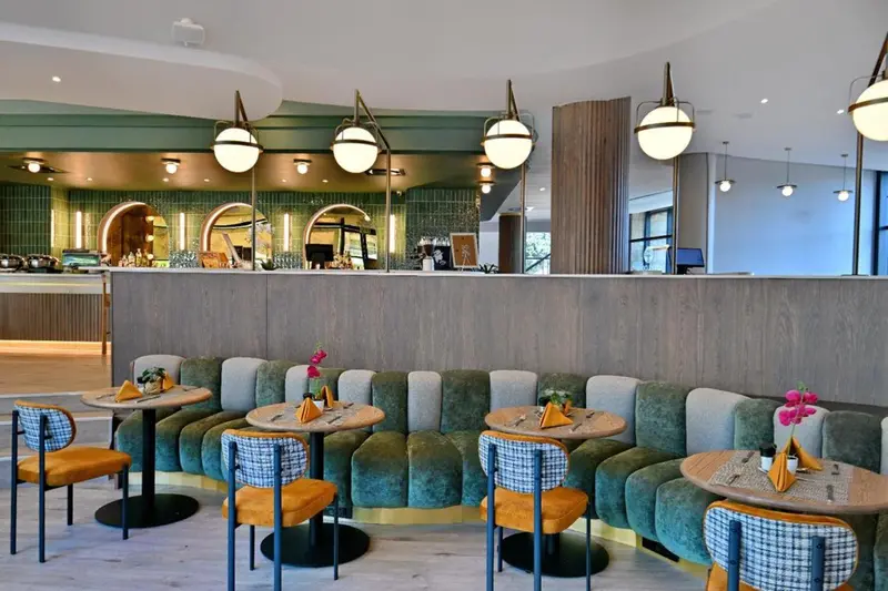 Une salle de restaurant lumineuse avec des tables dressées et des banquettes confortables.