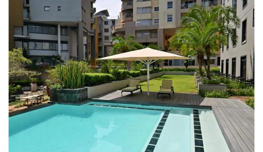 Espace extérieur avec piscine, pelouse et mobilier de détente.