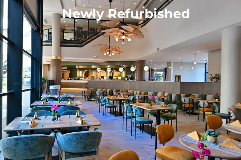 Une salle de restaurant lumineuse avec des tables dressées et des fenêtres donnant sur l'extérieur.