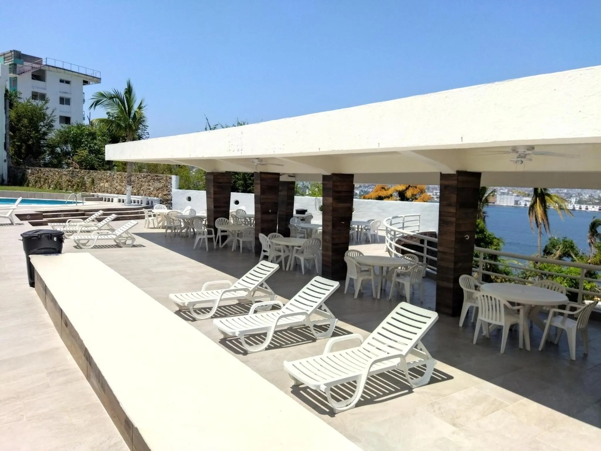 Terrasse avec transats et tables offrant une vue sur la mer.