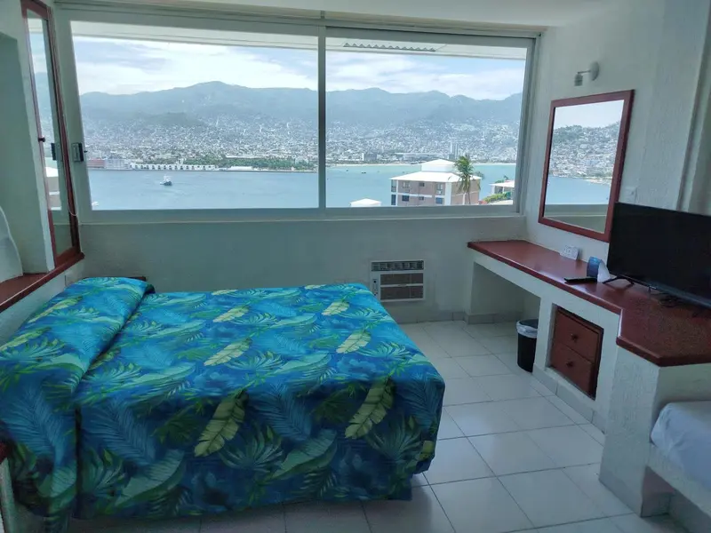Chambre lumineuse avec vue sur la ville et la mer.