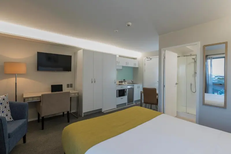 Une chambre lumineuse avec un espace bureau et une kitchenette.