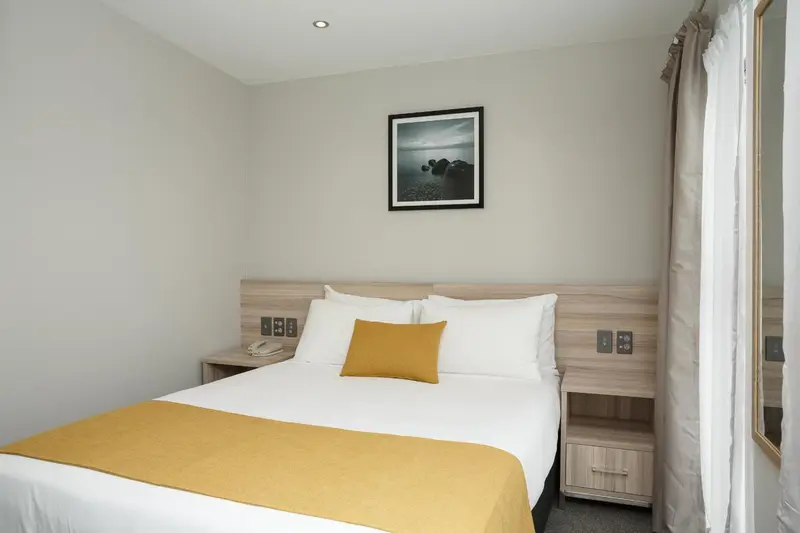 Une chambre lumineuse avec un grand lit recouvert d'une couverture jaune.