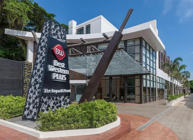 Façade moderne d'un bâtiment avec un logo et une végétation soignée.