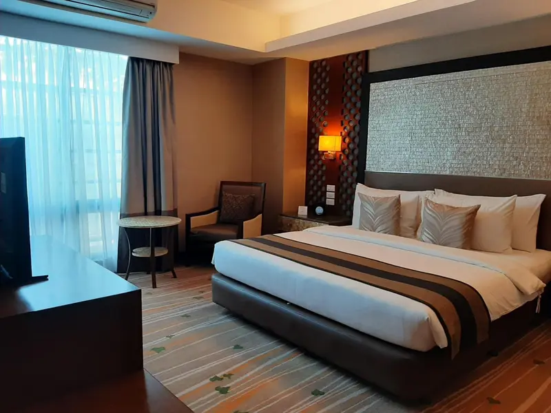 Une chambre d'hôtel moderne avec un grand lit et un fauteuil.