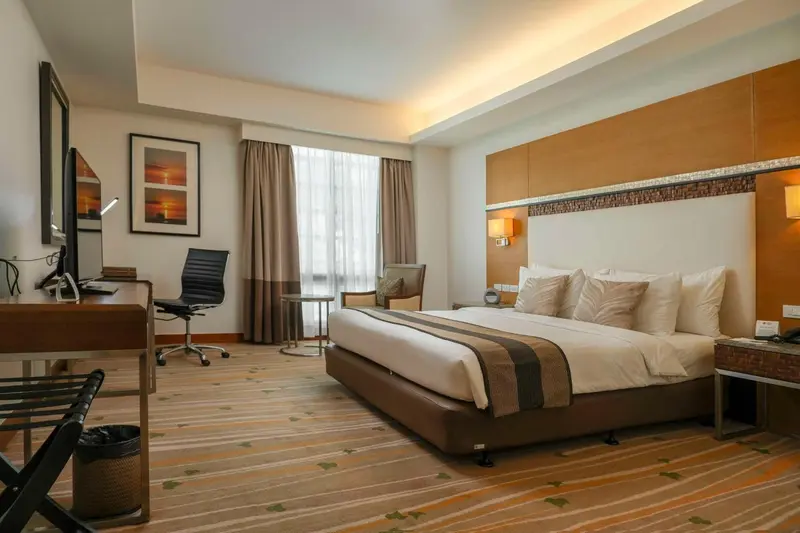 Chambre d'hôtel lumineuse avec un grand lit et un espace bureau.