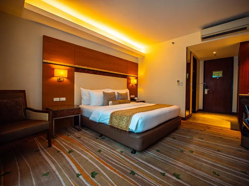 Chambre lumineuse avec un grand lit et un éclairage chaleureux.