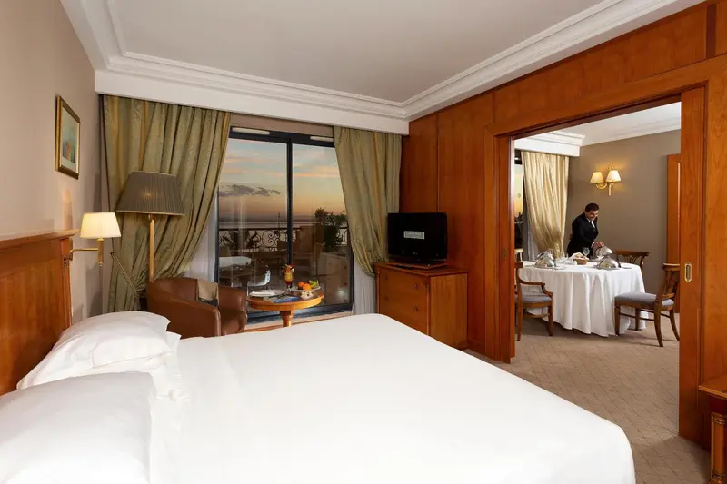 Chambre lumineuse avec un grand lit et vue sur la mer.