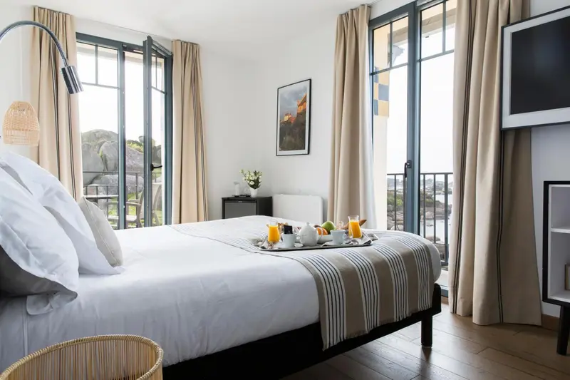 Une chambre lumineuse avec un lit préparé et un plateau de petit-déjeuner.