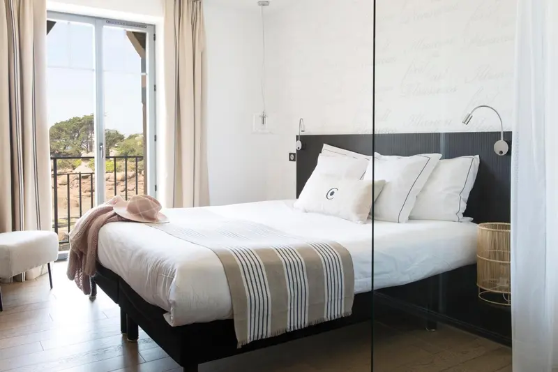 Une chambre lumineuse avec un grand lit et un accès à un balcon.