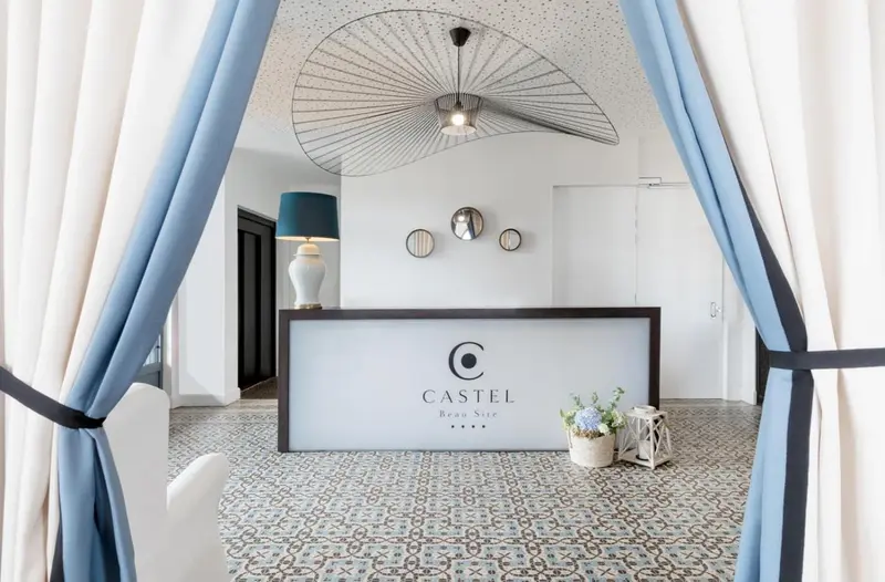 Un comptoir d'accueil lumineux dans un espace intérieur décoré de rideaux bleus et de motifs géométriques.