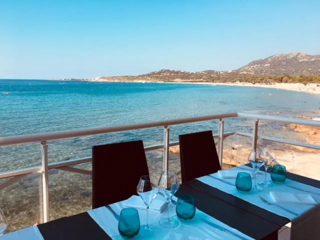 Une table est dressée sur une terrasse avec vue sur la mer et une plage.