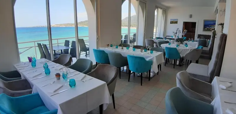 Une salle de restaurant lumineuse avec vue sur la mer et une plage.
