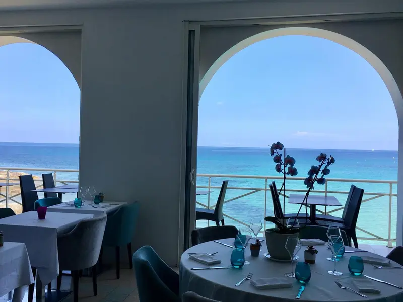 Une salle à manger lumineuse offre une vue dégagée sur la mer turquoise.