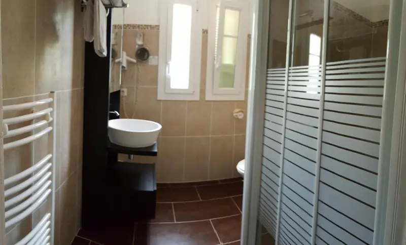 Une salle de bain moderne avec carrelage beige et sanitaires blancs.
