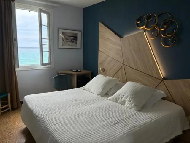 Une chambre lumineuse avec un lit blanc et une vue sur la mer.