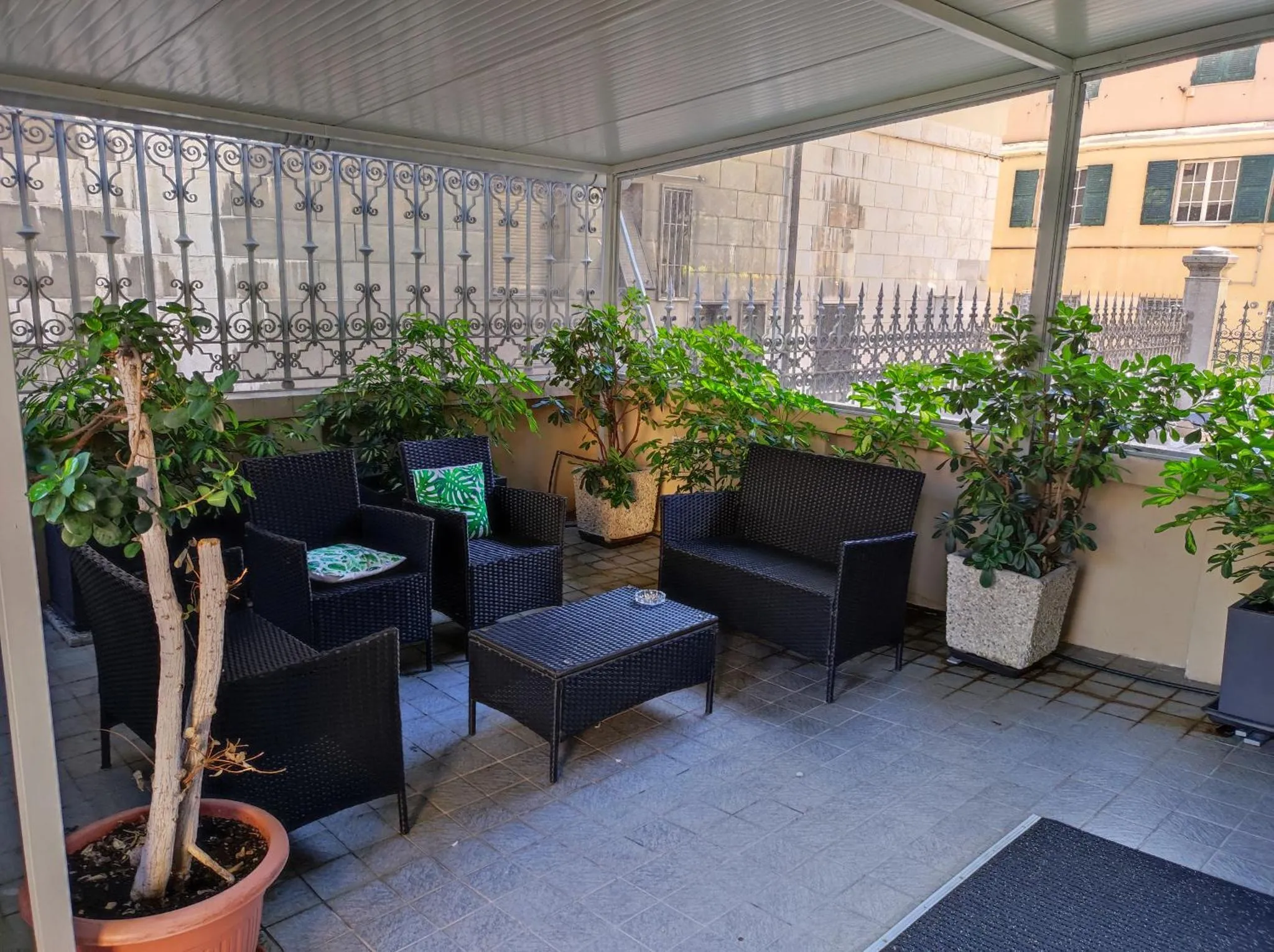 Espace de détente extérieur avec mobilier en résine tressée et plantes en pot.