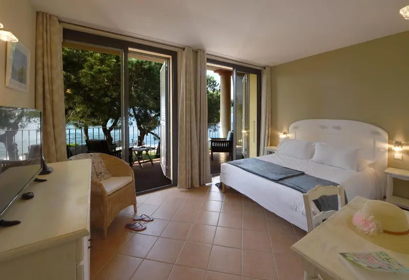 Une chambre lumineuse s'ouvre sur une terrasse avec vue sur la mer.